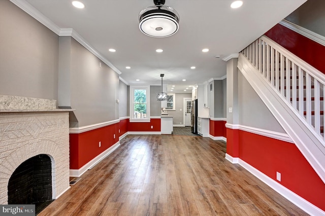 unfurnished living room with dark wood-type flooring, a fireplace, and crown molding