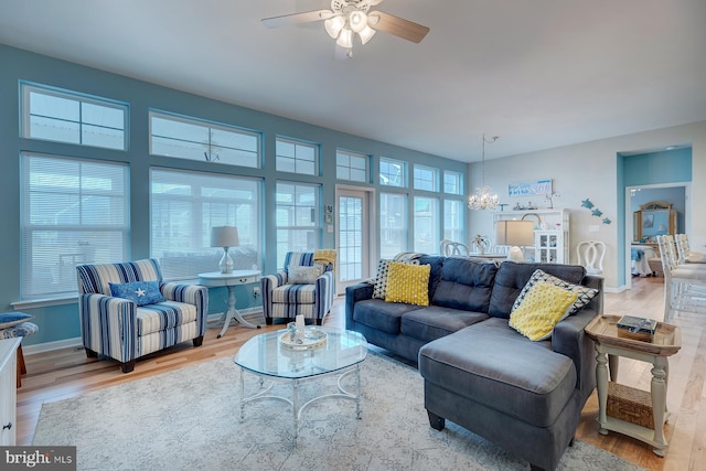 living room with ceiling fan with notable chandelier and light hardwood / wood-style floors