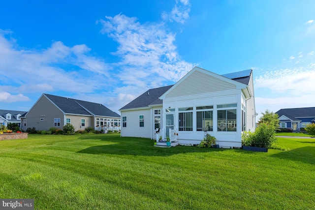 back of house with a sunroom and a yard