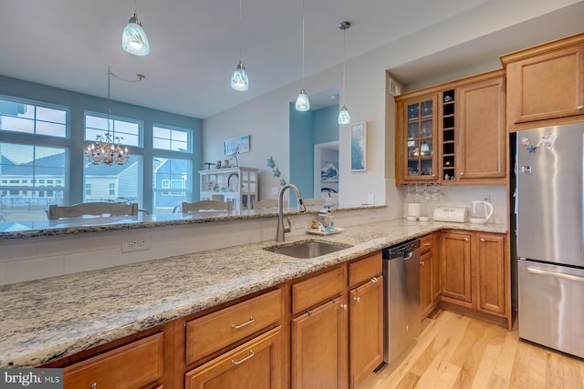 kitchen featuring light hardwood / wood-style floors, appliances with stainless steel finishes, decorative light fixtures, and light stone counters