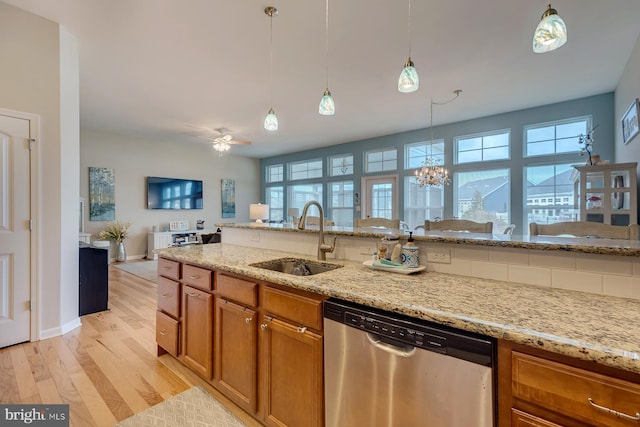 kitchen with stainless steel dishwasher, decorative light fixtures, sink, light hardwood / wood-style floors, and a wealth of natural light