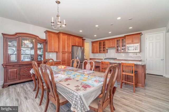 dining room with light wood-type flooring and a notable chandelier