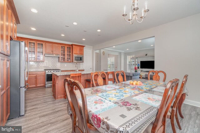 dining area featuring an inviting chandelier, sink, and light hardwood / wood-style floors