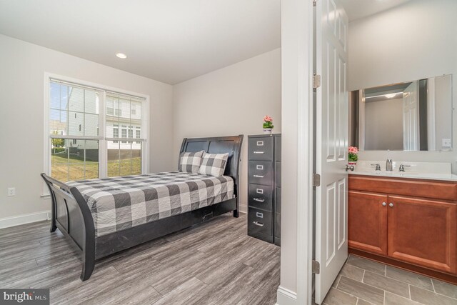 bedroom with sink and light hardwood / wood-style flooring