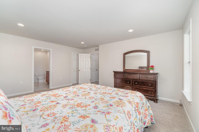 bedroom with light colored carpet and ensuite bathroom