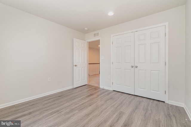 unfurnished bedroom with a closet and light wood-type flooring