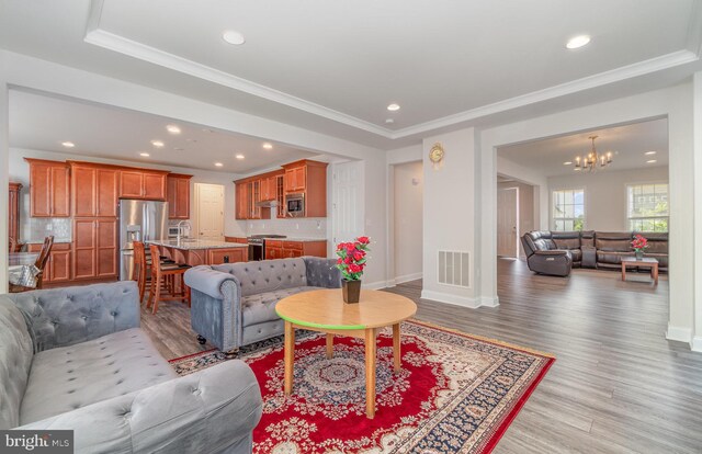 living room featuring a chandelier, light hardwood / wood-style flooring, and ornamental molding