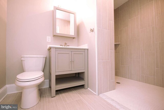 bathroom featuring tile patterned floors, tiled shower, vanity, and toilet