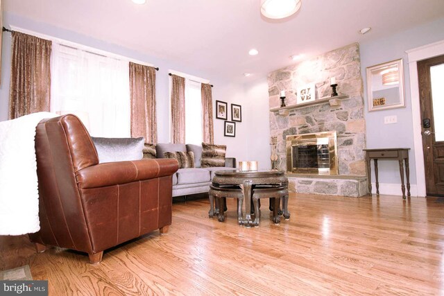 living room with plenty of natural light, a stone fireplace, and light wood-type flooring