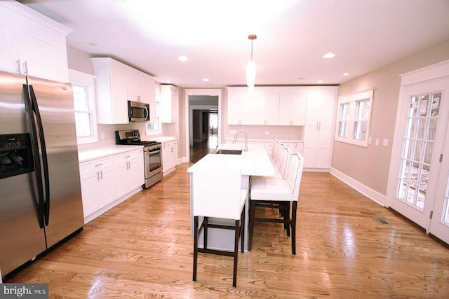 kitchen with sink, appliances with stainless steel finishes, light hardwood / wood-style flooring, and white cabinetry