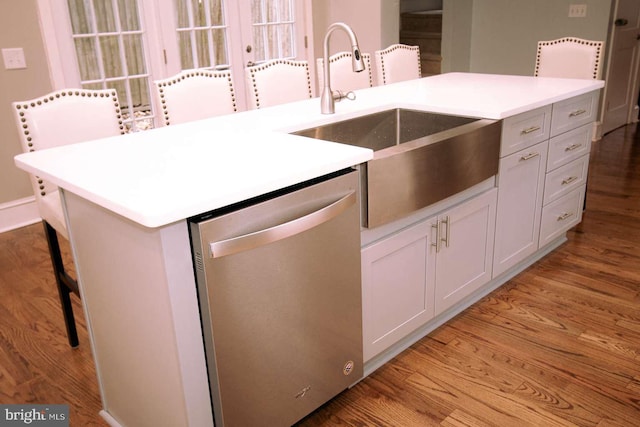 kitchen with white cabinets, dishwasher, a kitchen island with sink, light hardwood / wood-style floors, and sink