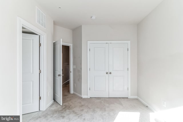 unfurnished bedroom featuring a closet and light carpet