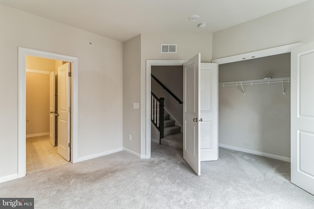 unfurnished bedroom with light colored carpet and a closet