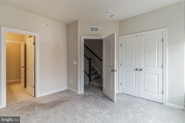 unfurnished bedroom featuring light colored carpet and a closet