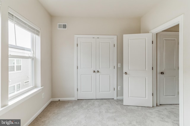 unfurnished bedroom with light colored carpet and a closet