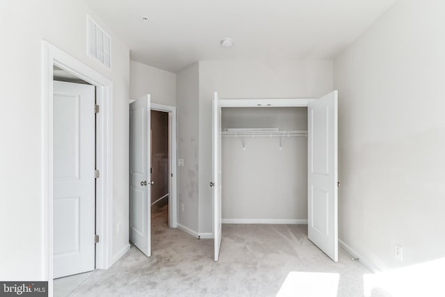 unfurnished bedroom with light colored carpet and a closet