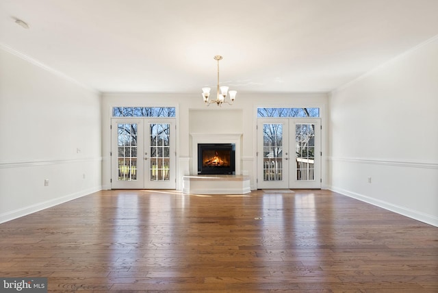 unfurnished living room with french doors, dark wood-type flooring, an inviting chandelier, and plenty of natural light