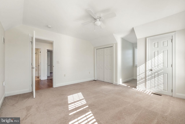 unfurnished bedroom featuring ceiling fan, lofted ceiling, and light colored carpet