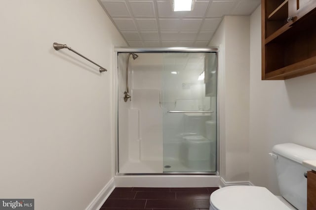 bathroom featuring hardwood / wood-style floors, a shower with shower door, and toilet