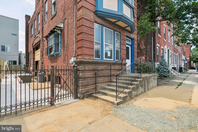 exterior space with brick siding, fence, and a gate