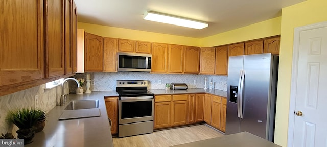 kitchen featuring stainless steel appliances, sink, light wood-type flooring, and tasteful backsplash