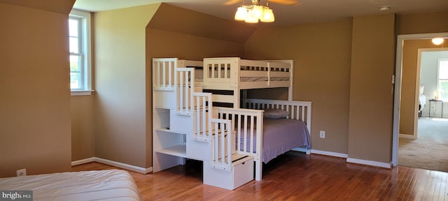 unfurnished bedroom featuring lofted ceiling, hardwood / wood-style flooring, and multiple windows