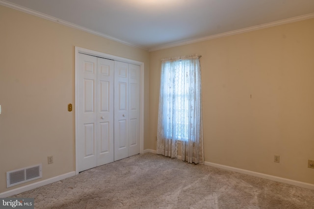 unfurnished bedroom with baseboards, visible vents, crown molding, and carpet flooring