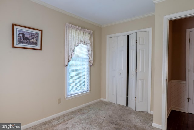 unfurnished bedroom with baseboards, a closet, carpet flooring, and crown molding