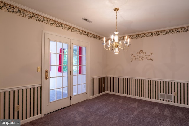 spare room with carpet floors, visible vents, crown molding, and an inviting chandelier