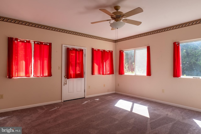 carpeted spare room featuring a healthy amount of sunlight, ceiling fan, and baseboards