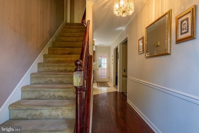 stairway featuring a chandelier, baseboards, crown molding, and hardwood / wood-style floors