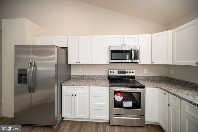 kitchen featuring appliances with stainless steel finishes, light stone countertops, vaulted ceiling, and white cabinets