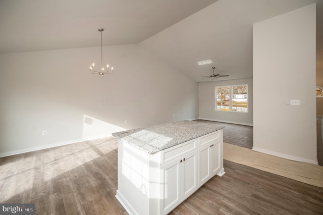 kitchen with decorative light fixtures, a kitchen island, hardwood / wood-style flooring, light stone countertops, and white cabinets