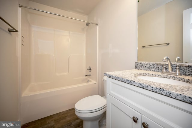 full bathroom featuring hardwood / wood-style flooring, vanity, washtub / shower combination, and toilet