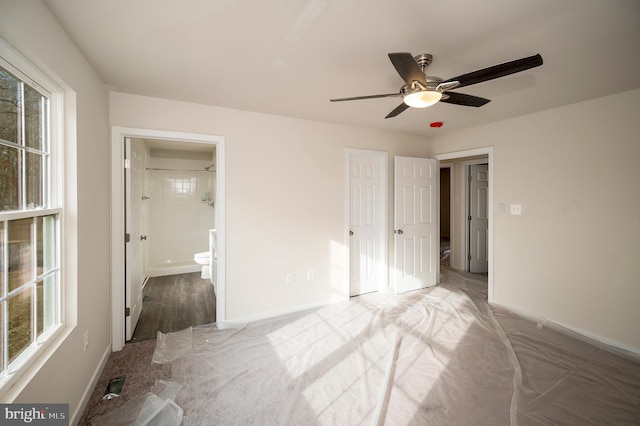 unfurnished bedroom with ceiling fan, ensuite bath, carpet, and multiple windows