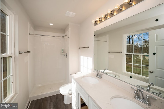 bathroom featuring wood-type flooring, toilet, vanity, and a shower