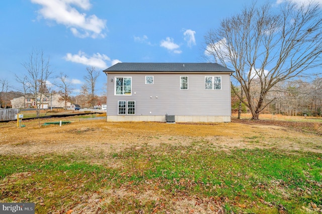 rear view of property featuring central AC and a lawn