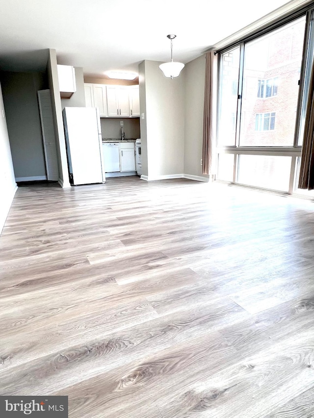 unfurnished living room with sink, light hardwood / wood-style flooring, and expansive windows