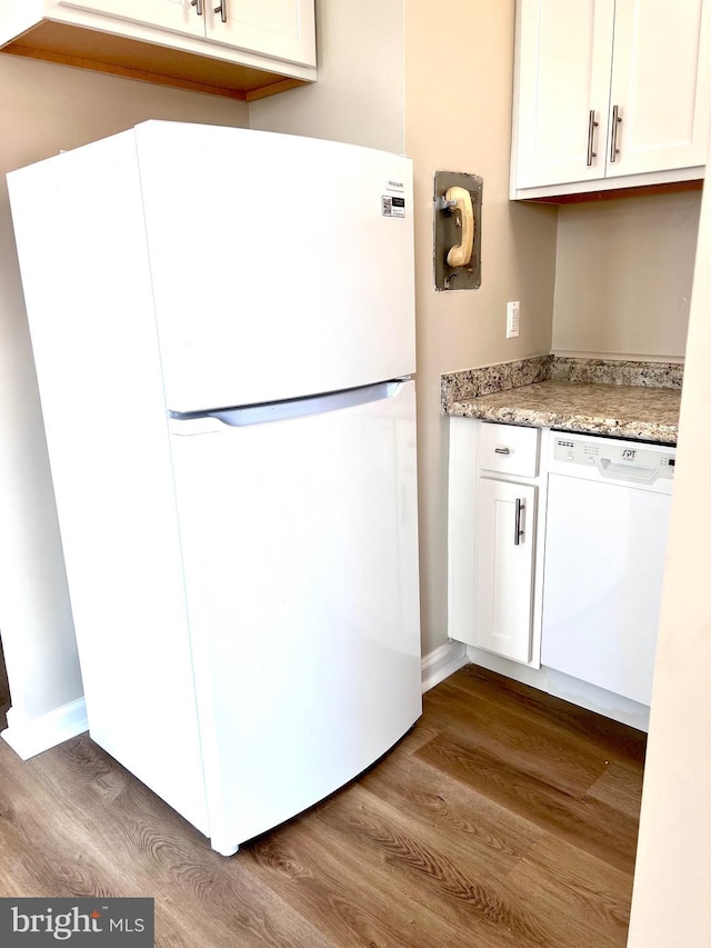 kitchen with light stone counters, white appliances, white cabinets, and hardwood / wood-style flooring