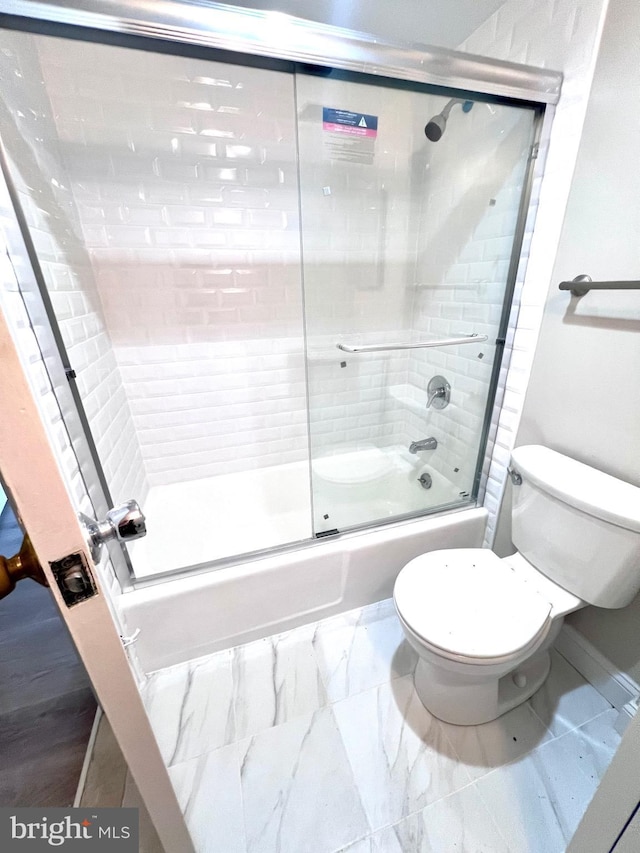 bathroom featuring bath / shower combo with glass door and toilet