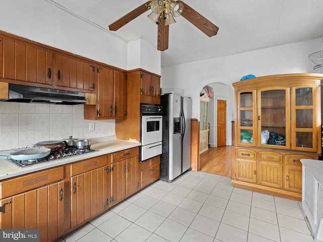 kitchen featuring tasteful backsplash, ceiling fan, stainless steel appliances, and light tile patterned floors