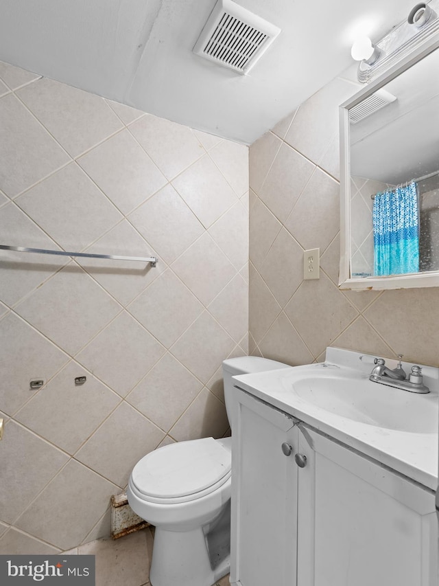 bathroom with vanity, toilet, and tile walls