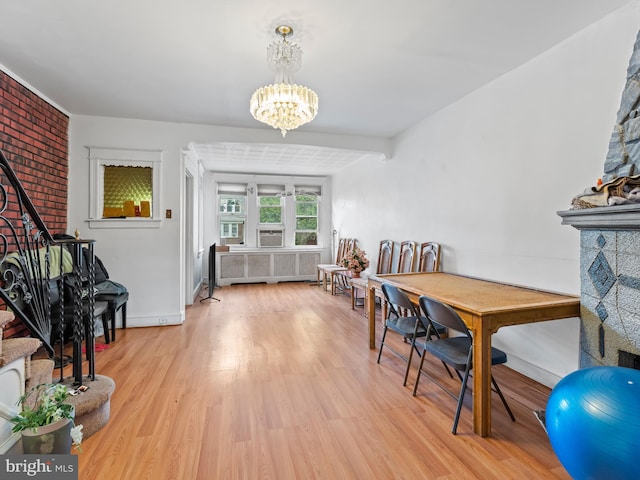 dining area with an inviting chandelier, radiator, and light wood-type flooring