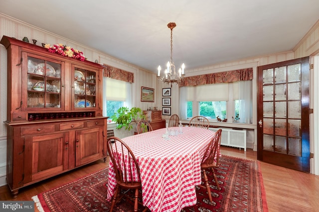 dining space with ornamental molding, a chandelier, radiator heating unit, and light wood-type flooring