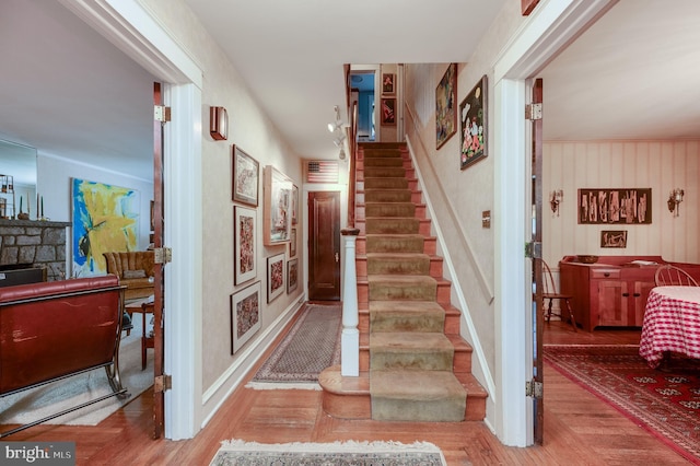 staircase with a stone fireplace and hardwood / wood-style floors