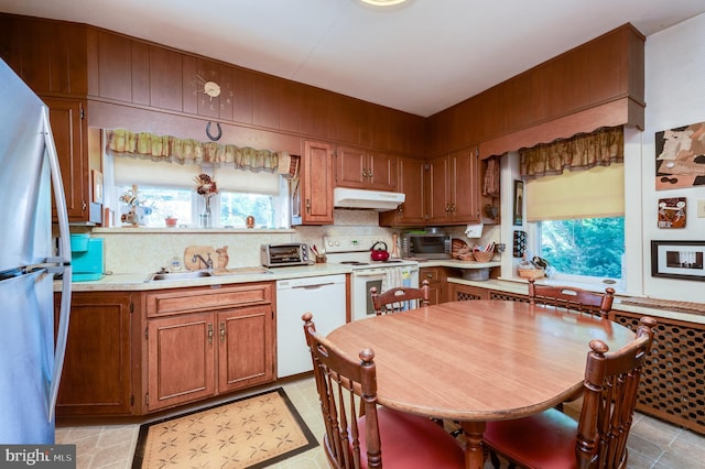 kitchen featuring sink, white appliances, and decorative backsplash