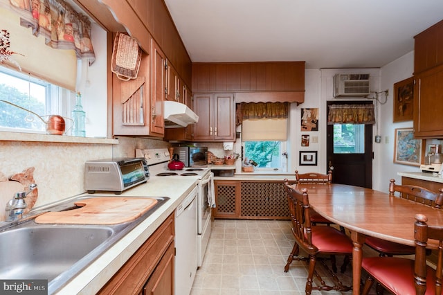 kitchen featuring plenty of natural light, sink, a wall mounted air conditioner, and white appliances