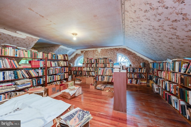 living area with a textured ceiling, vaulted ceiling, and wood-type flooring