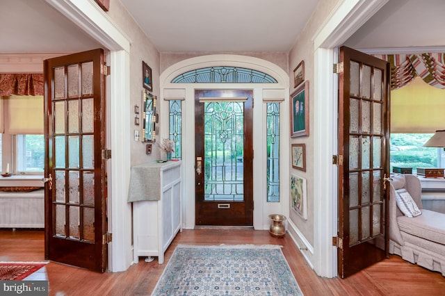 foyer entrance featuring radiator heating unit, hardwood / wood-style flooring, and a wealth of natural light