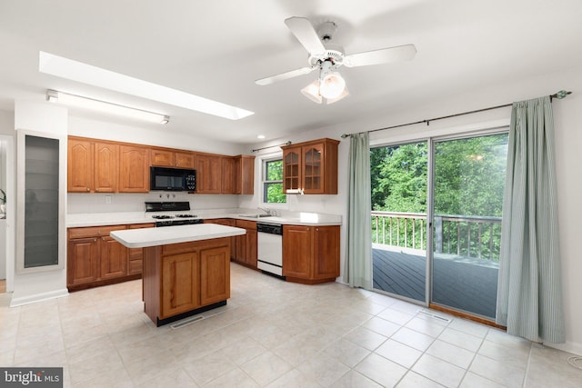 kitchen featuring sink, white appliances, ceiling fan, a skylight, and a kitchen island